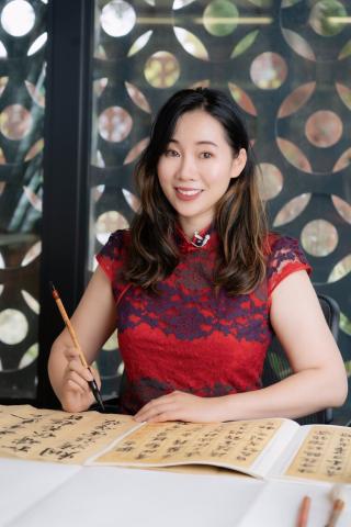 Photo of calligraphist Jojo Liu smiling as she works